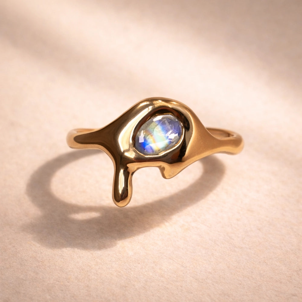 Close up of a custom ring by Ruinette featuring a rainbow moonstone set in 14k yellow gold