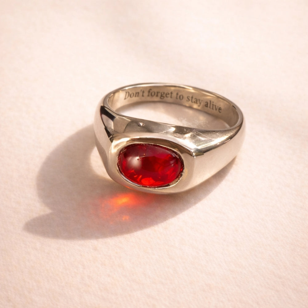 Close up of a custom Ruinette signet ring featuring a carved garnet set in 10k white gold
