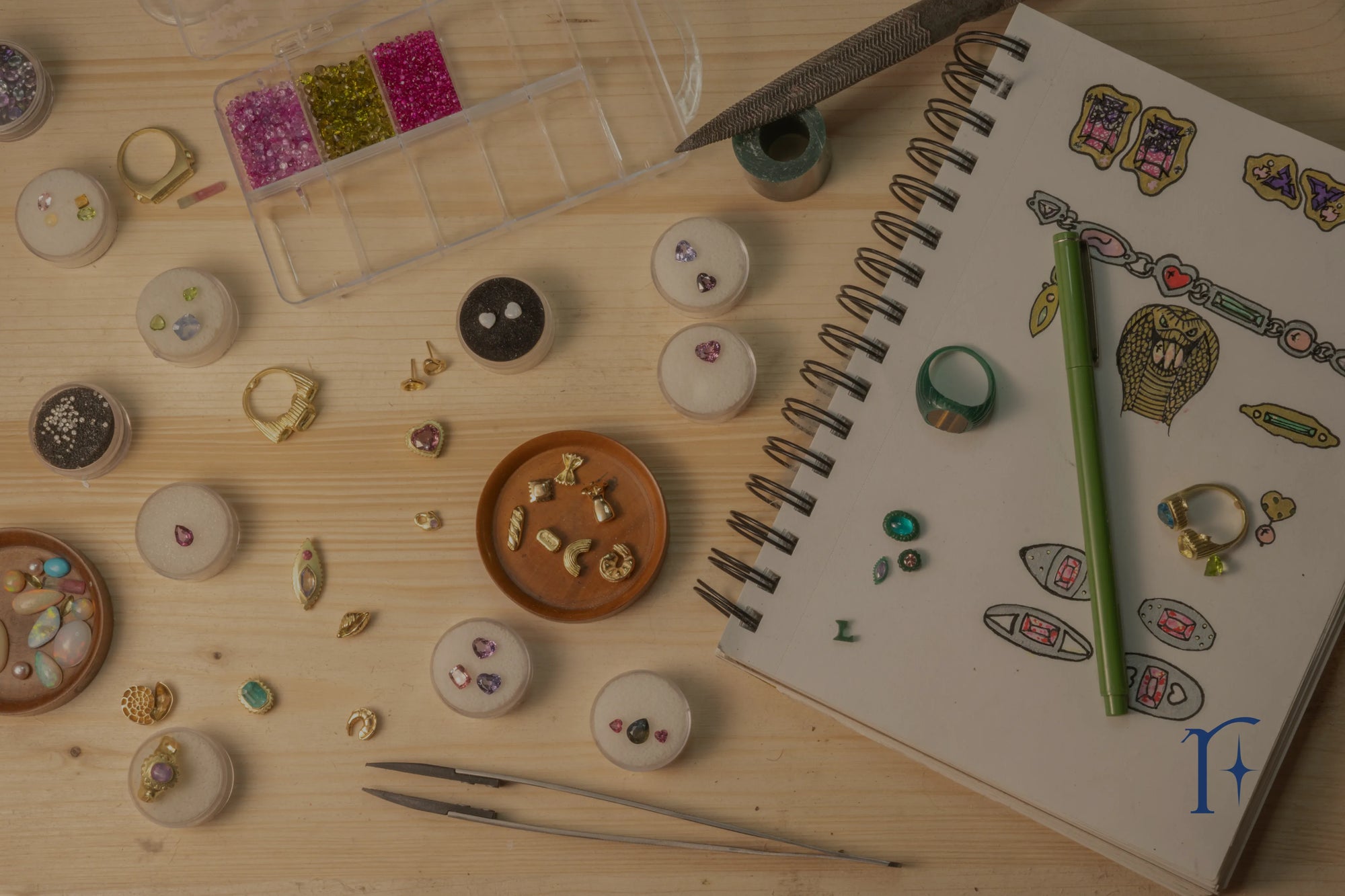 A high-level view of Ruinette workspace featuring sketchbook, precious stones, in-progress pieces and tools