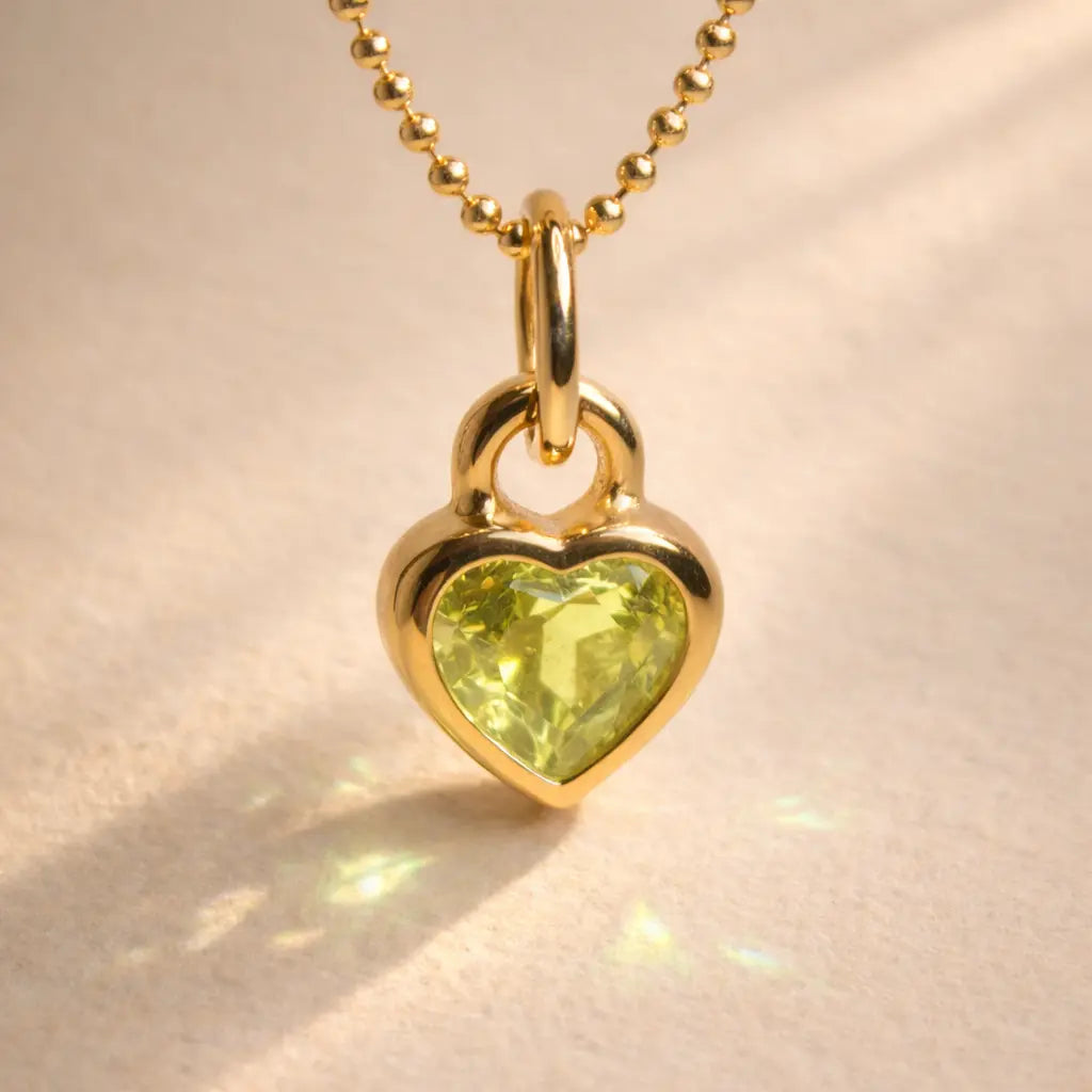 Ruinette Becky Peridot Heart Charm in 18k gold featuring faceted yellow-green peridot gemstone in heart-shaped bezel setting on gold ball chain