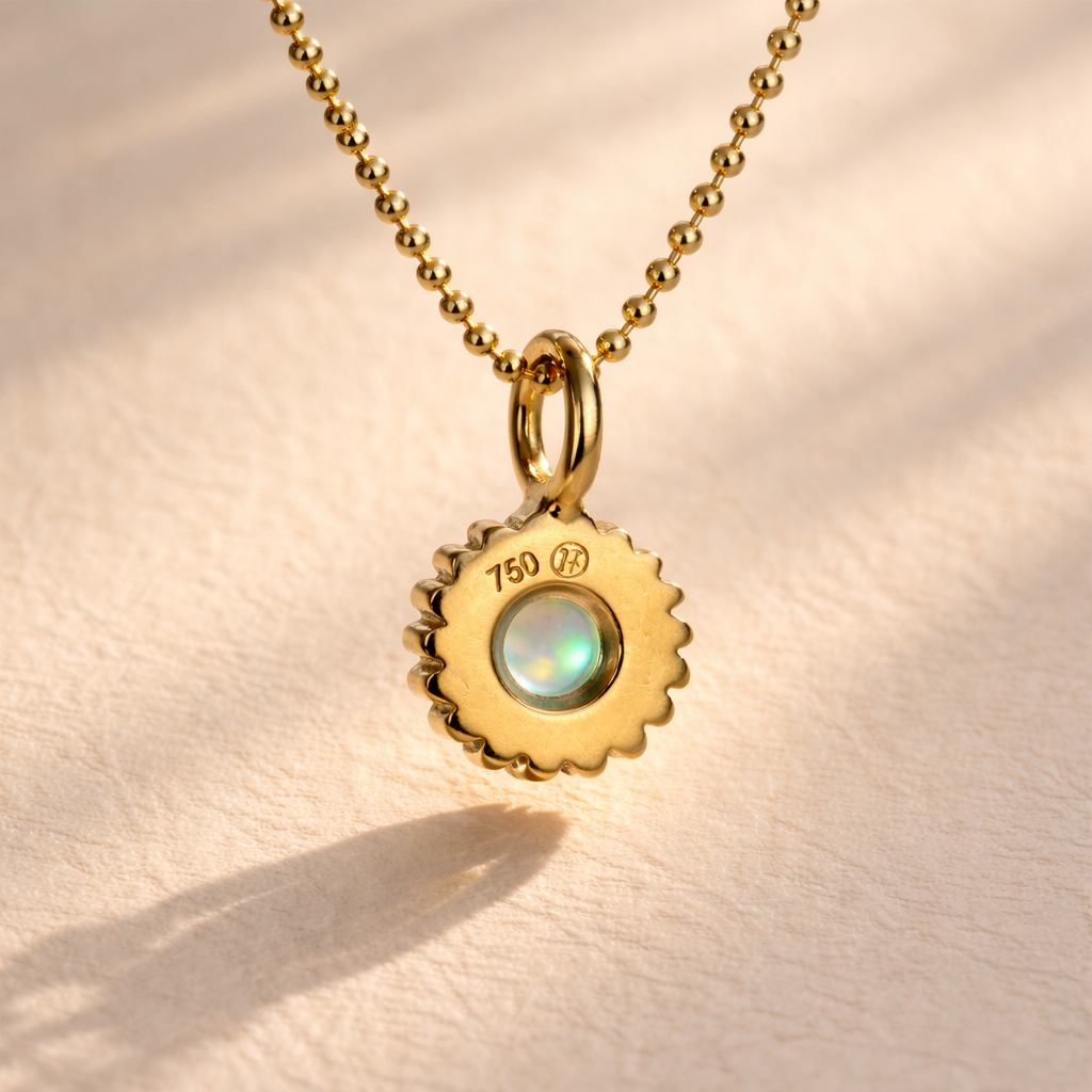 The Full Moon Baby Rib Opal Charm's back showcases its 18k yellow gold design, featuring an Australian opal cabochon. Handcrafted by Ruinette Bijoux, it's a unique jewelry piece.