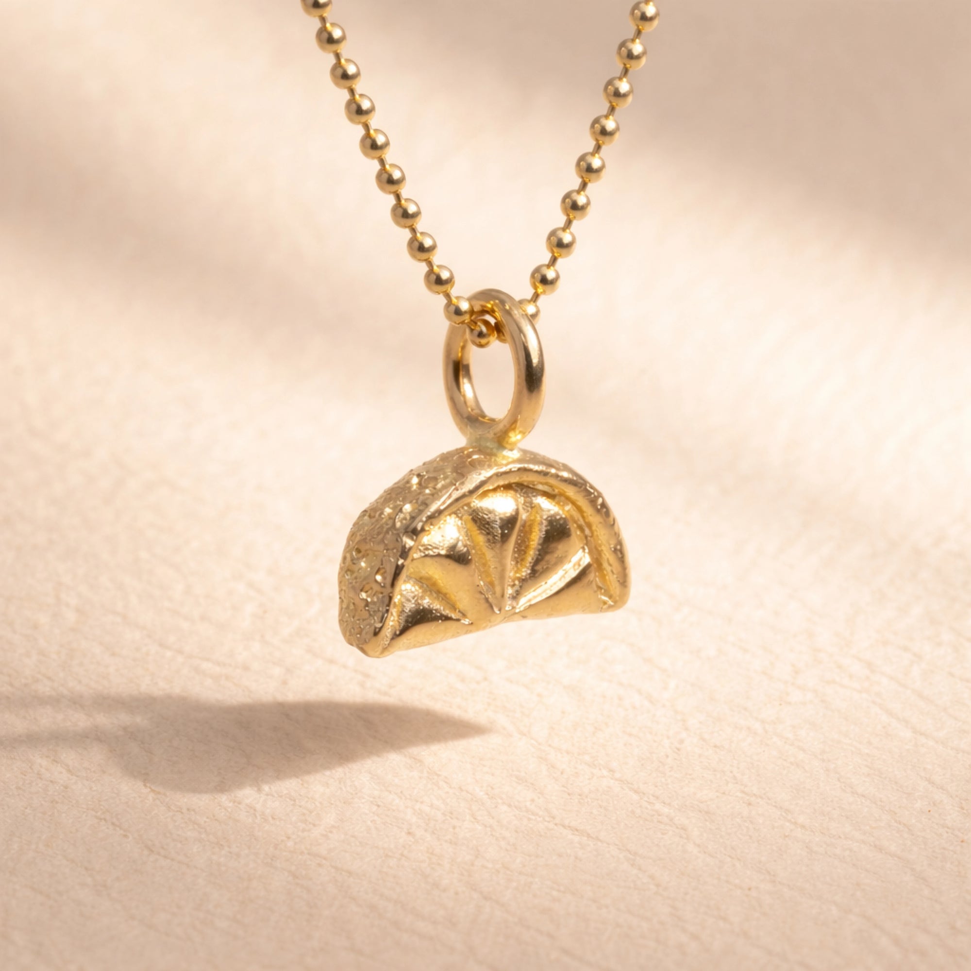 Ruinette Lemon Slice Charm close-up showing 18k yellow gold dome design with radial pattern and granulated texture on ball chain necklace