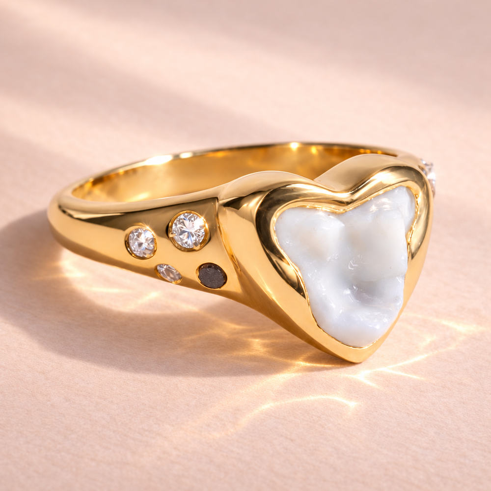 Penny's tooth ring at an angle crafted in 14k yellow gold. It features a dog tooth with brilliant cut white and black diamonds, and a pink tourmaline. A unique piece by Ruinette Bijoux.